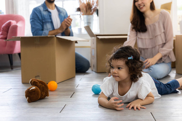 Cute daughter with parent. Happy family in living room. Moving new house a lot of parcel box. Father mother and daughter relax together at home. - Photo, Image