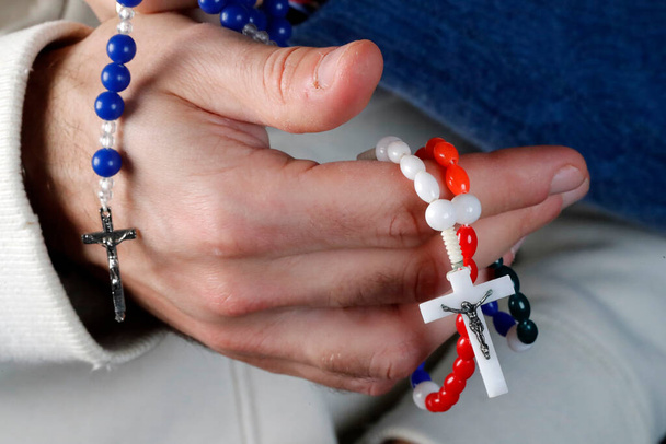 Katolikus férfi és nő együtt imádkoznak otthon. Zárja be a kezét imagyöngyökkel. Franciaország.  - Fotó, kép