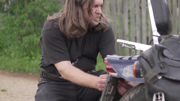 Brutaali mies pyörä korjaa hänen moottoripyörä kesällä kadulla - Materiaali, video