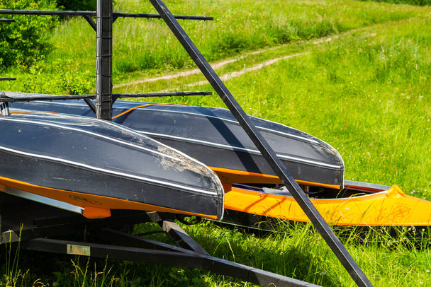 Orangefarbene Kajaks am Ufer auf dem Gras und für den Transport an einem sonnigen Tag beladen - Foto, Bild