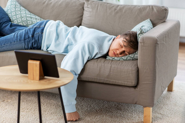 bored man with tablet pc lying on sofa at home - Φωτογραφία, εικόνα