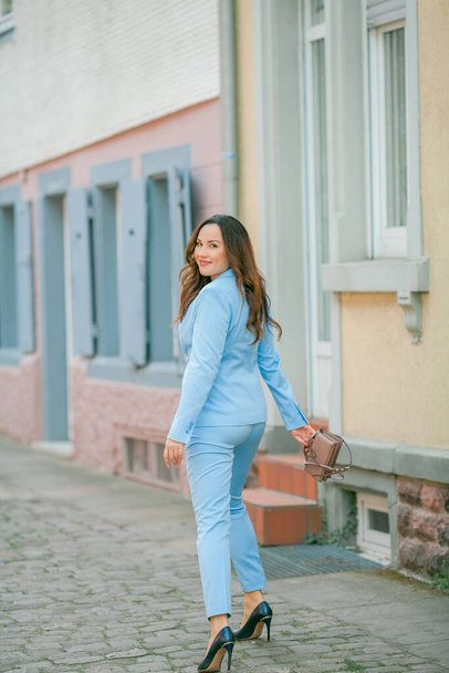 Portrait of a beautiful young woman in a blue suit with a bouquet of tulips. - Fotografie, Obrázek