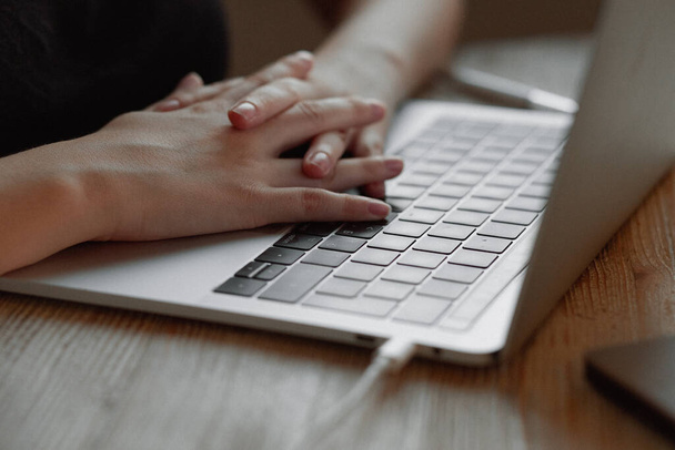 Dziewczyna pracuje w domu dla laptopa. Ręce są złożone z zamkiem i leżą na klawiaturze - Zdjęcie, obraz