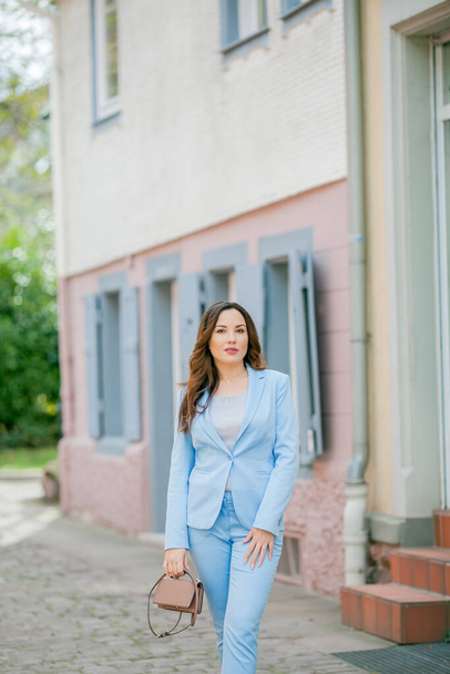 Portrait of a beautiful young woman in a blue suit with a bouquet of tulips. - Foto, afbeelding