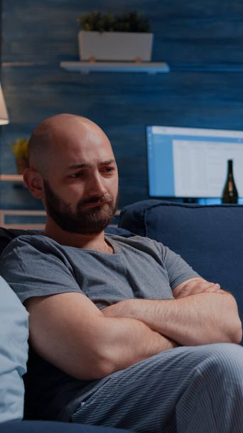 Frustrated man staring in space sitting alone on sofa feeling depressed - Photo, Image