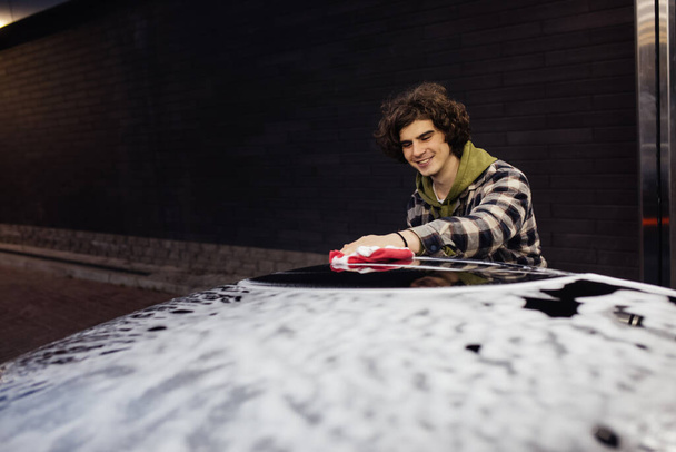 Happy man with detergent washing car in foam on self service wash  - Foto, Imagem