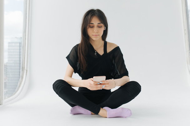 brunette armenian woman messaging on mobile phone while sitting with crossed legs - Φωτογραφία, εικόνα