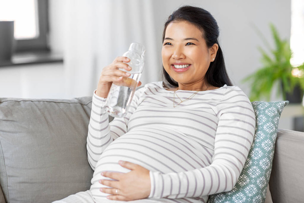 pregnant woman with water in glass bottle at home - Foto, Bild