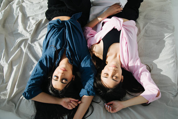 overhead view of two armenian women in casual clothes sleeping on white bedding - Photo, Image
