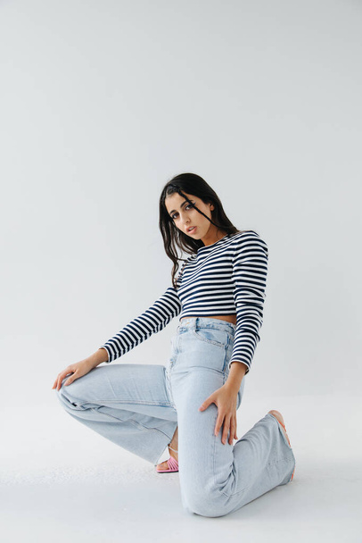 pretty armenian woman in jeans and striped pullover posing on white background - Fotoğraf, Görsel
