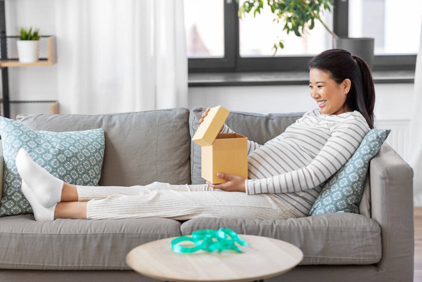 happy pregnant woman opening gift box at home - Photo, image