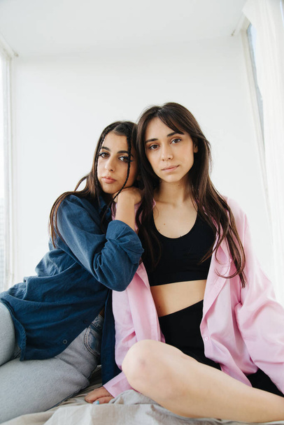 young armenian woman leaning on shoulder of friend while sitting on bedding - Foto, Bild