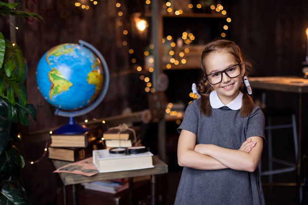 schoolgirl puts on glasses. Back to school concept. A girl nerd in a school uniform with pigtails. Primary School. Home work place. Classroom. Hunger for knowledge. Study education.  - Foto, Imagem
