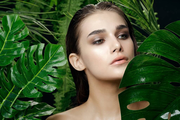 woman with bare shoulders green leaves Exotic clean skin - Фото, изображение