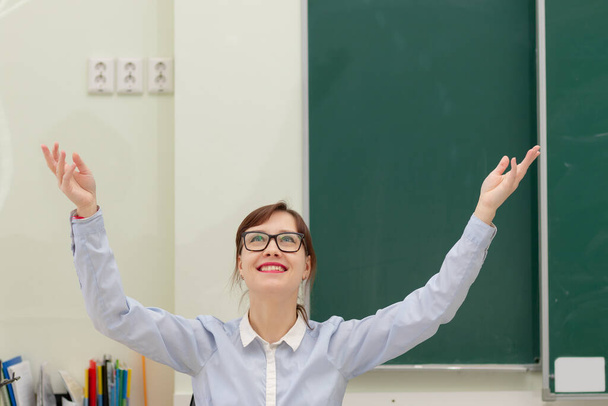 İş yerindeki sevimli genç bayan öğretmen görevini tamamladıktan sonra elini kaldırdı. - Fotoğraf, Görsel