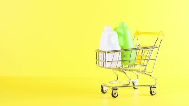 Ostoskori, jossa pullot keltaisella pohjalla, lähikuva. Musta perjantai ostokset ja alennus käsite - Materiaali, video