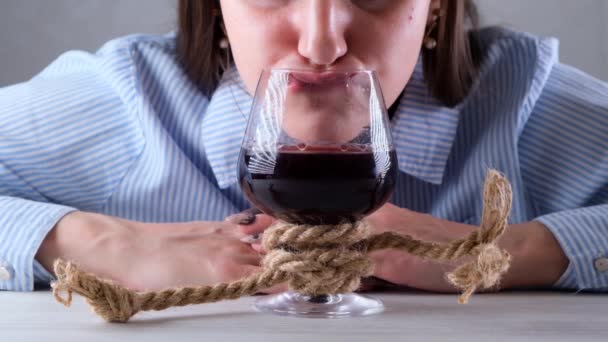 ワイングラスにジュートロープを結んだ女性のおかしい飲み物。アルコール依存症の概念。アルコール依存症の治療の問題 - 映像、動画