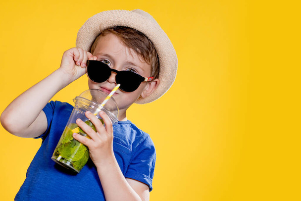 Portrait of a beautiful boy. Happy child. European boy in a hat, summer t-shirt with lemonade. Summer, vacation, vacation, sun, heat, sea, beach. Face for advertising - Zdjęcie, obraz