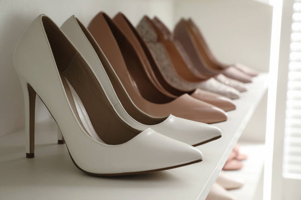 Different stylish women's shoes on shelf in dressing room, closeup - Фото, зображення