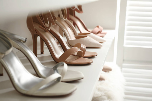 Different stylish women's shoes on shelf in dressing room, closeup - Фото, изображение