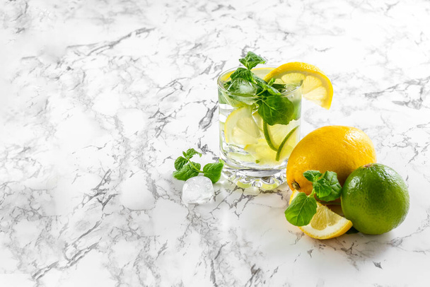 レモン、ライム、ミントのスライスと大理石のテーブルの上に飾られたガラスに氷とシトラスレモネード。新鮮な夏の飲み物。孤立してる。コピースペース。高品質の写真 - 写真・画像