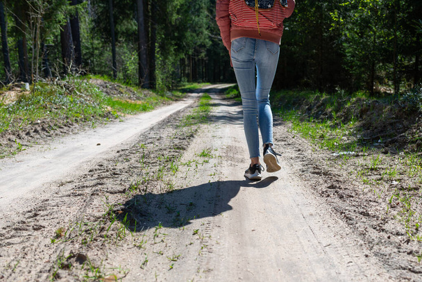 Une touriste fille avec un sac à dos le long de la route dans les bois.. - Photo, image
