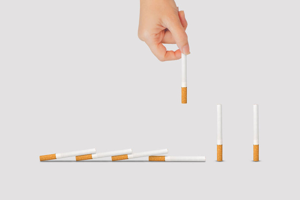 No Smoking Concept: Mano sosteniendo y sacando la pieza de cigarrillo de la fila de cigarrillos (camino de recorte). - Foto, imagen