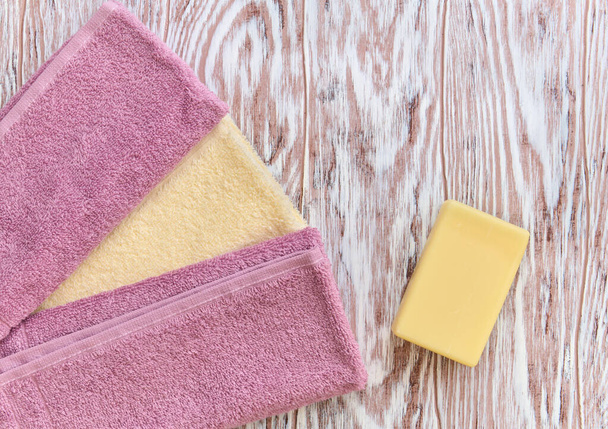 Piece of toilet soap and towel on a wooden background - Fotó, kép