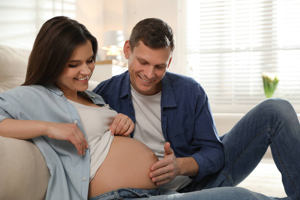 Mujer embarazada joven con su marido en casa - Foto, imagen