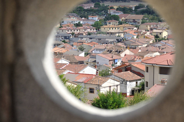 Blick auf die Häuser eines Dorfes aus einem kreisrunden Fenster - Foto, Bild