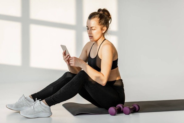 Woman with phone on a fitness training - Zdjęcie, obraz