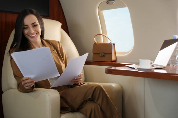 Businesswoman working with documents in airplane during flight - Zdjęcie, obraz