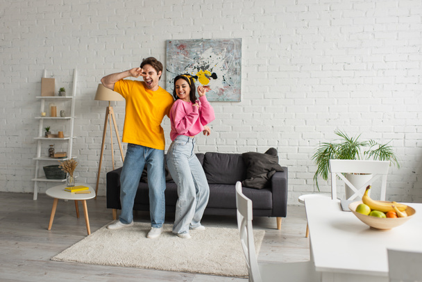 smiling young couple in casual clothes dancing in modern loft - Zdjęcie, obraz
