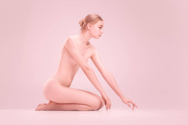Graceful fragile young naked beautiful girl posing isolated on pink studio background. Concept of beauty, purity, tenderness and grace. - Fotó, kép