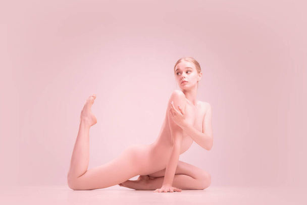 Graceful fragile young naked beautiful girl posing isolated on pink studio background. Concept of beauty, purity, tenderness and grace. - Valokuva, kuva