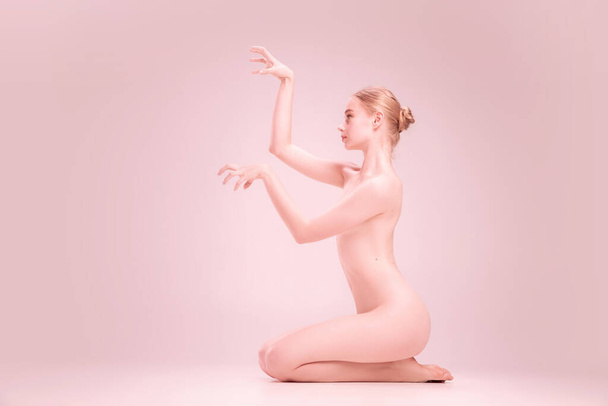Young naked beautiful girl looking at camera isolated on pink studio background. Concept of beauty, purity, tenderness and grace. - Foto, immagini