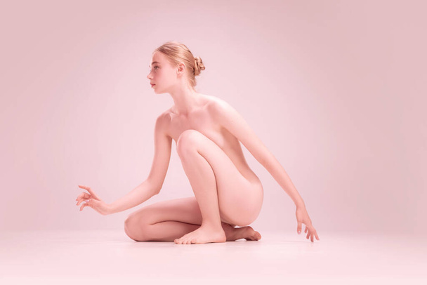 Graceful fragile young naked beautiful girl posing isolated on pink studio background. Concept of beauty, purity, tenderness and grace. - Photo, Image