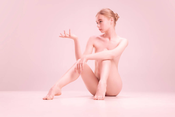 Young naked beautiful girl looking at camera isolated on pink studio background. Concept of beauty, purity, tenderness and grace. - Fotoğraf, Görsel