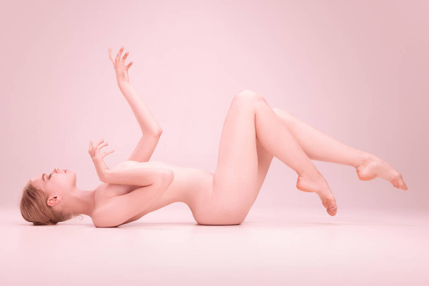 Graceful fragile young naked beautiful girl posing isolated on pink studio background. Concept of beauty, purity, tenderness and grace. - Valokuva, kuva