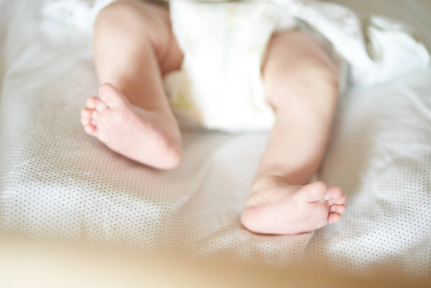 Baby legs on white sheet, newborn baby 1 month, care and love - Photo, Image