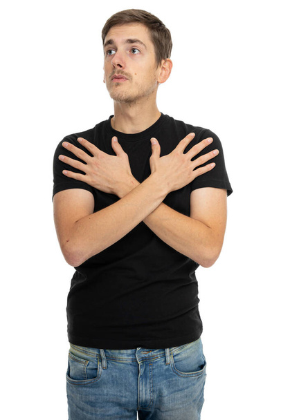młody przystojny przystojny szczupły biały człowiek z brązowymi włosami dotykając jego ramiona w czarny koszula w niebieski dżinsy odizolowane na białym tle - Zdjęcie, obraz