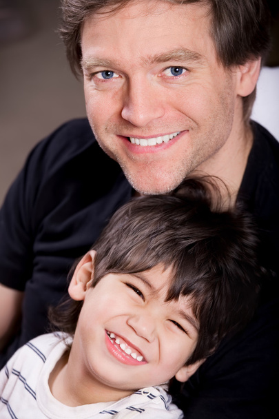 Гарний молодий батько посміхається з неповносправним маленьким сином
 - Фото, зображення