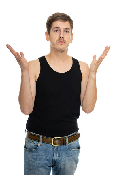 Young handsome tall slim white man with brown hair with spread hands in black undershirt isolated on white background - Fotó, kép