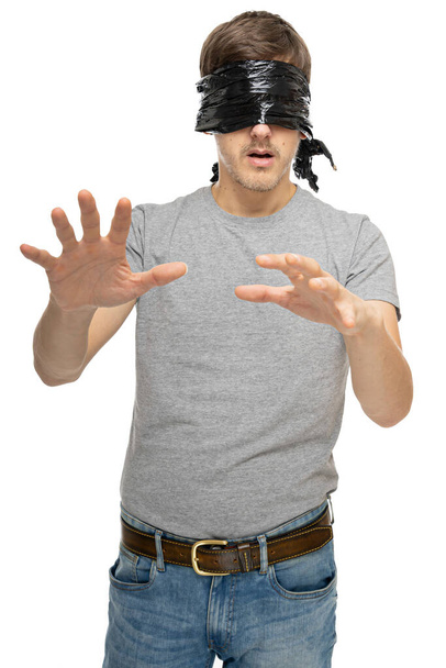 Young handsome tall slim white man with brown hair with black plastic bag covering his eyes in gray shirt isolated on white background - Photo, Image