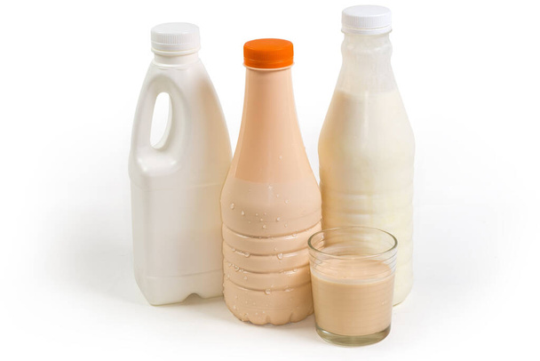 Ферментоване запечене молоко в склянці проти пластикових пляшок різних молочних продуктів на білому тлі, вид збоку
  - Фото, зображення