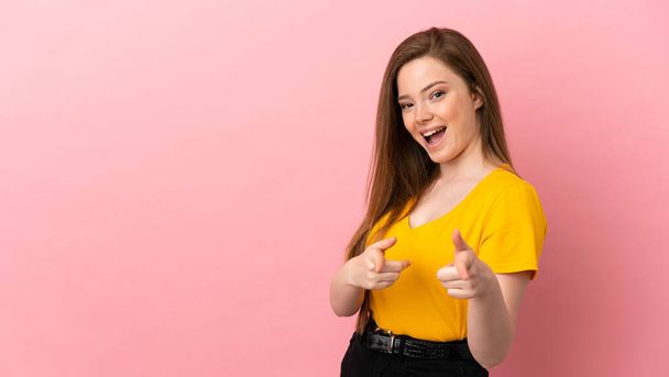 tiener meisje over geïsoleerde roze achtergrond wijzen naar de voorkant en glimlachen - Foto, afbeelding