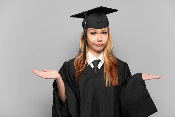 Young university graduate girl over isolated background having doubts while raising hands - Foto, Imagen