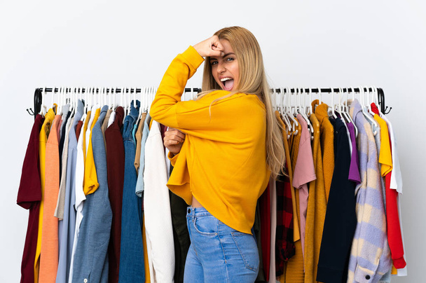 Young Uruguayan blonde woman in a clothing store doing strong gesture - Foto, afbeelding