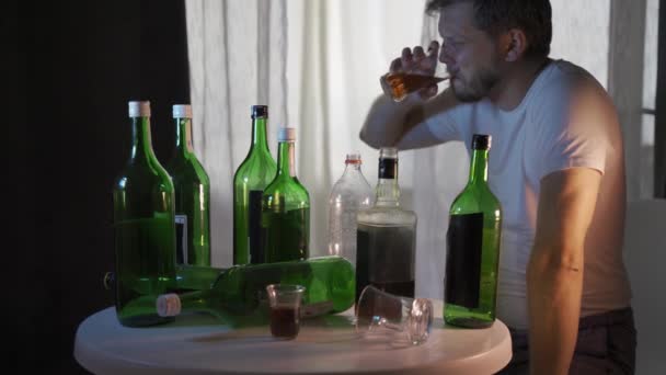silueta de una silueta de un alcohólico anónimo bebiendo detrás de botellas de alcohol, alcoholismo - Imágenes, Vídeo