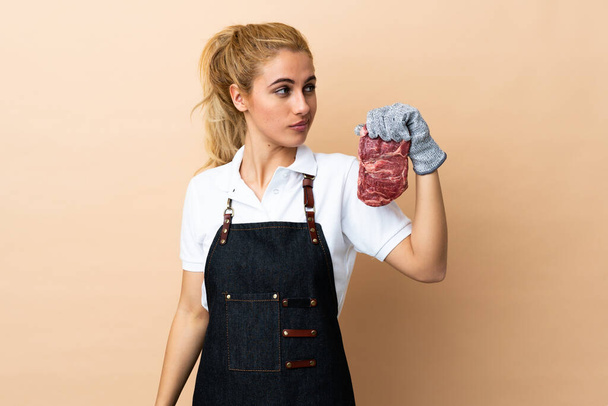 Metzgerfrau trägt Schürze und serviert vor isoliertem Hintergrund frisch geschnittenes Fleisch - Foto, Bild